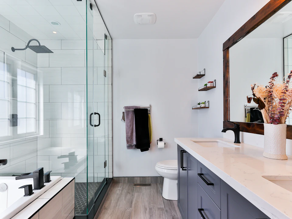 Un baño moderno con ducha de vidrio y un mueble de lavabo azul
