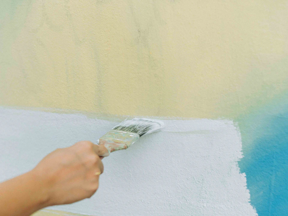 Una brocha aplicando una nueva capa de pintura en una pared interior